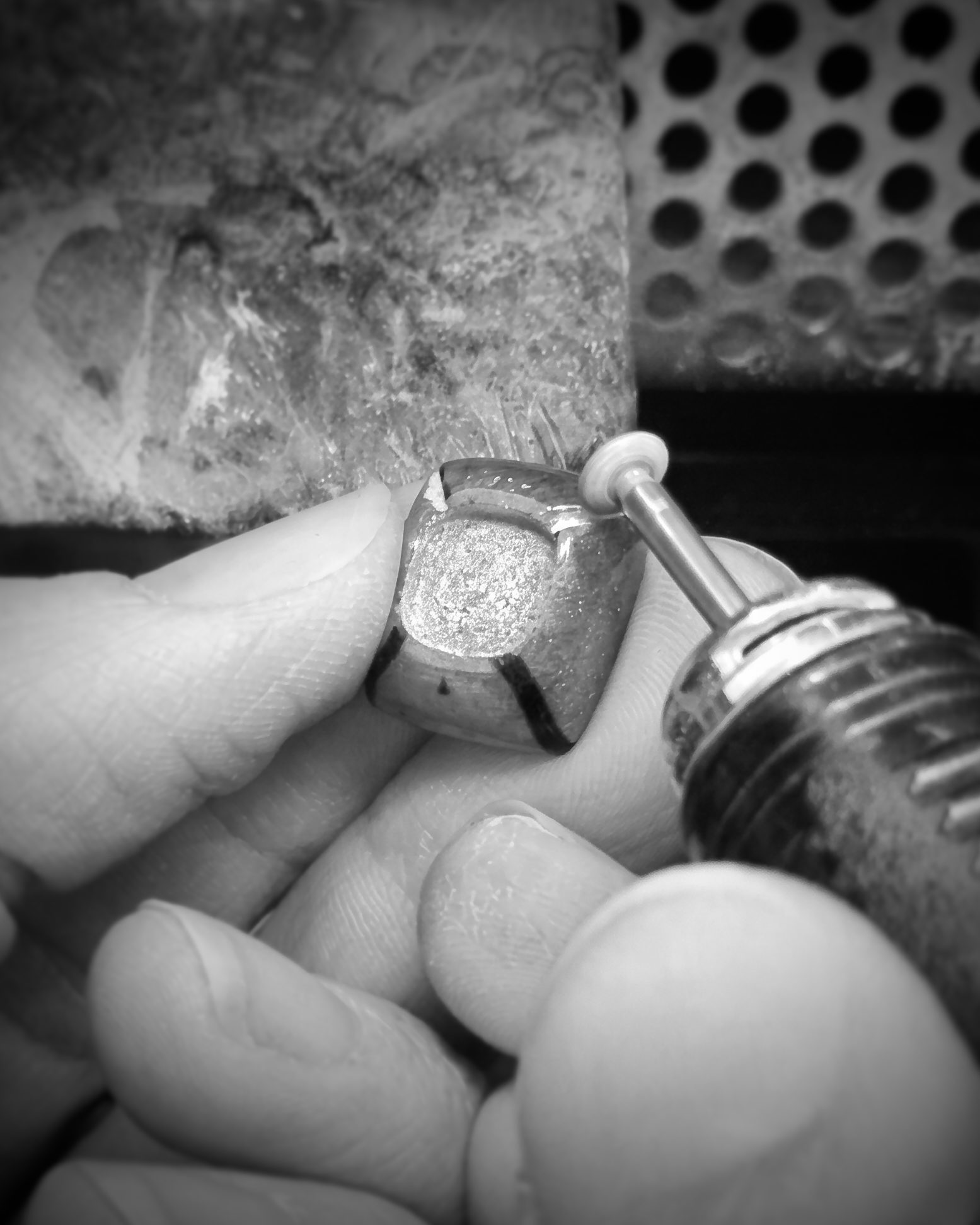 Close-up of a dental procedure: a drill bit shaping a tooth held by gloved fingers.