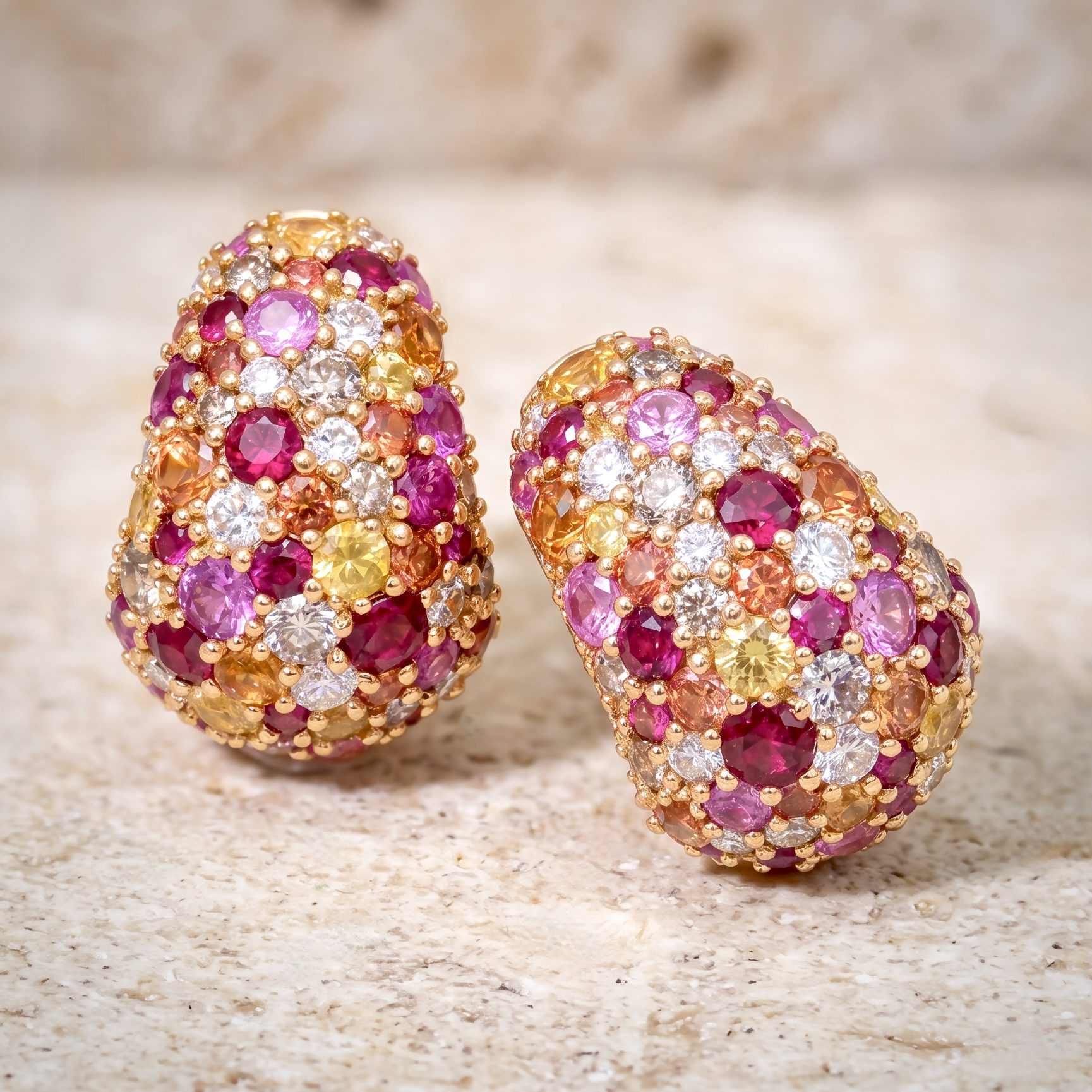 Two decorative eggs encrusted with multicolored gems and gold beads on a beige speckled surface.