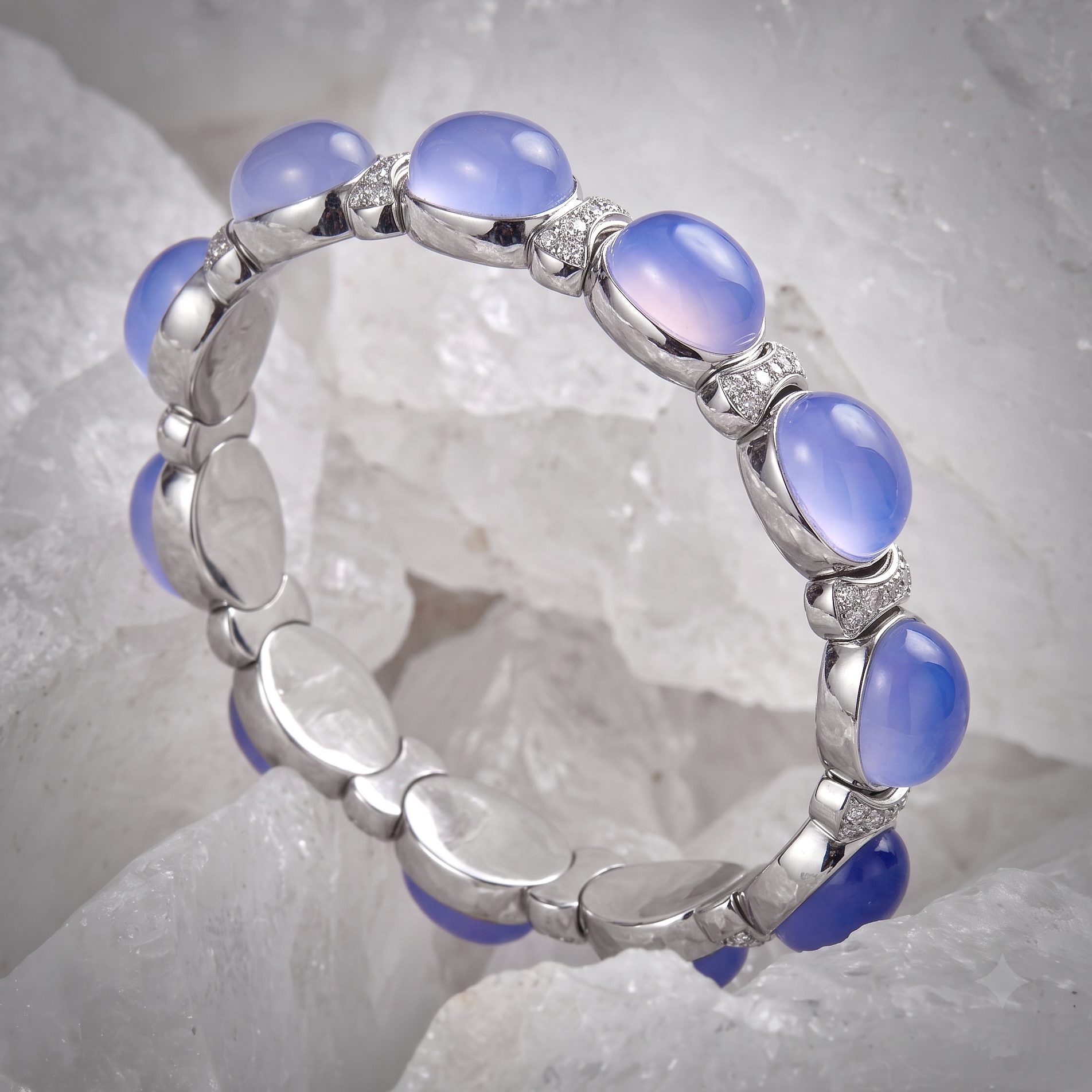 Silver bracelet with lavender cabochon beads linked in curved segments on a pale crystal background.