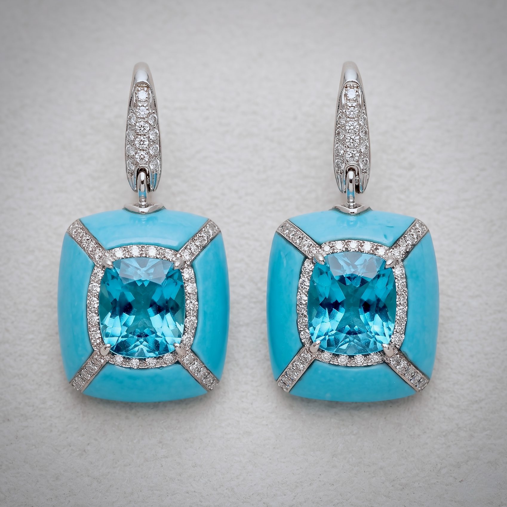 Pair of turquoise earrings with large blue gemstone centers surrounded by diamond-studded settings.