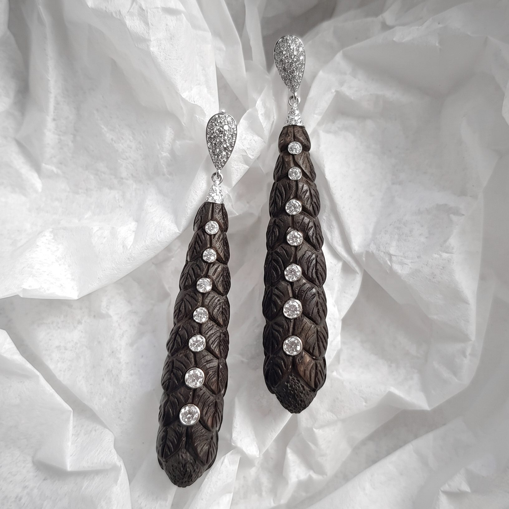 Pair of long drop earrings with dark carved wooden tassels and glittering silver caps.