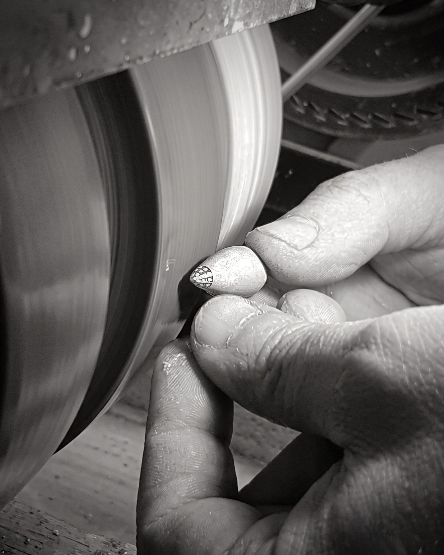 Close-up of gloved hands guiding a spinning sanding belt on a workshop machine.