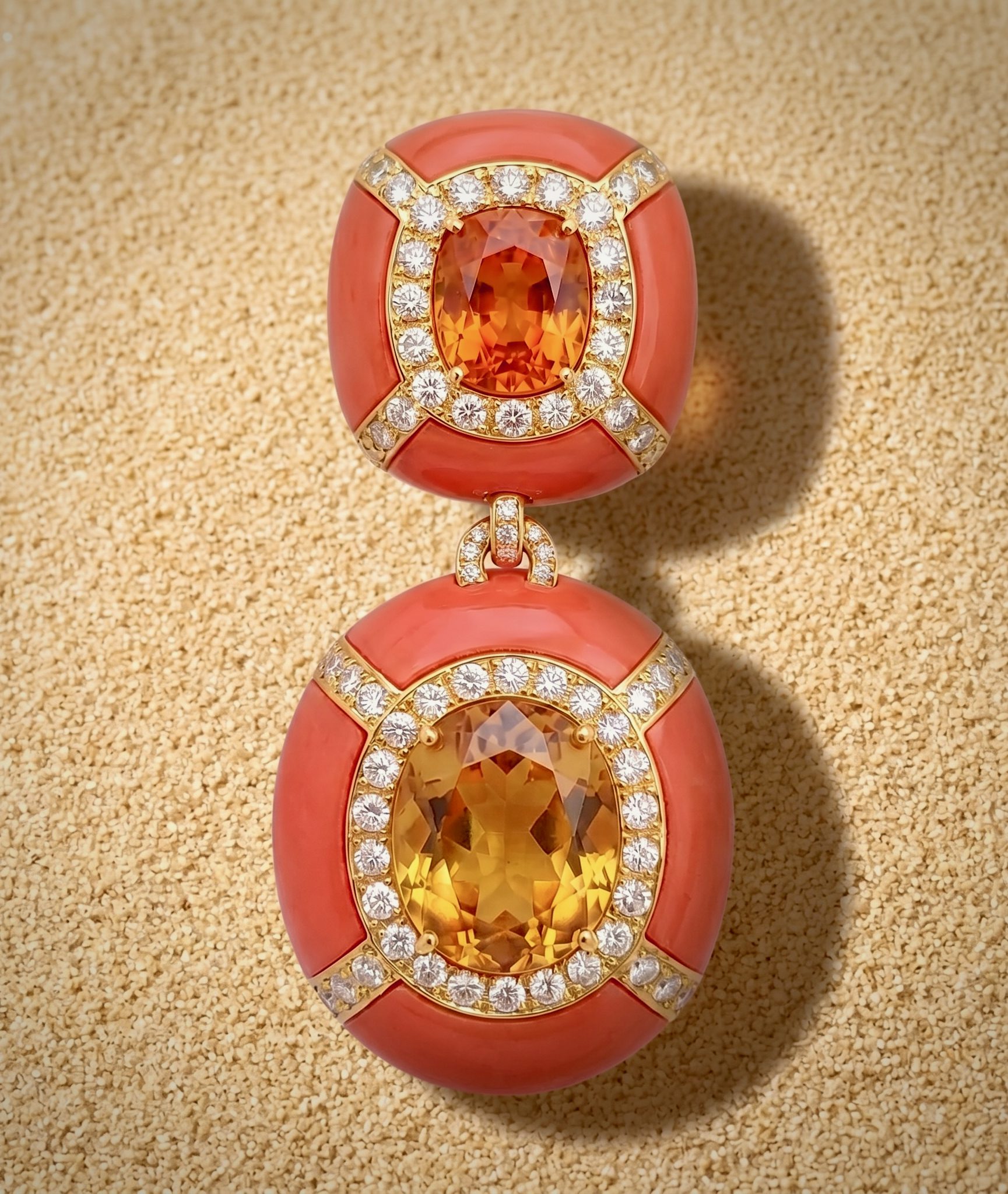 Close-up of a coral-orange gem ring with a large central orange stone surrounded by a diamond-studded gold halo on a beige textured background